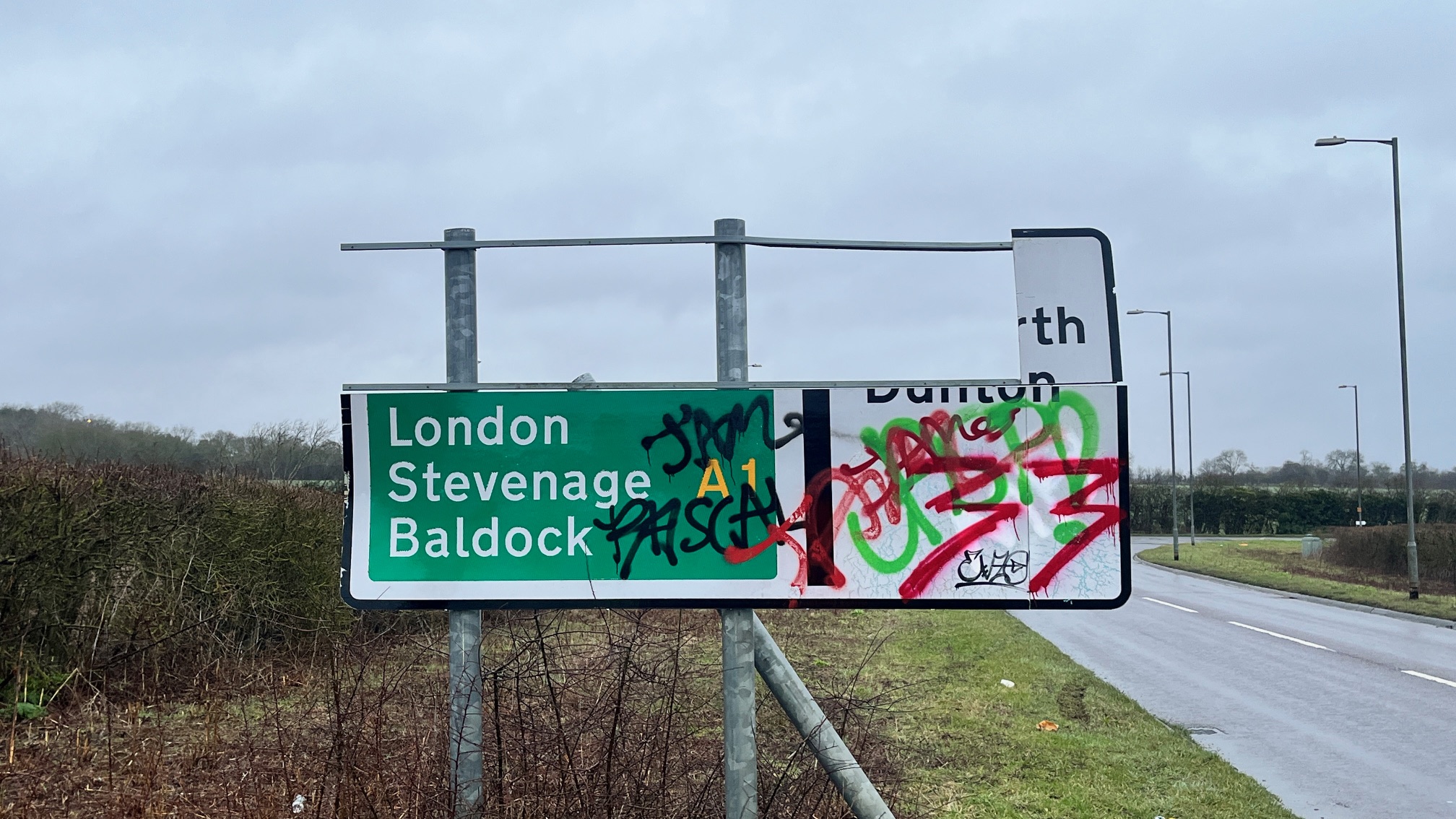 A broken road sign covered in graffiti.