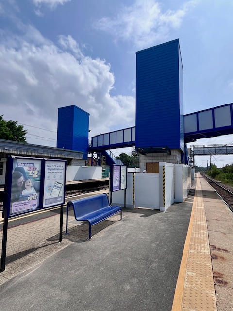 The two bright blue lift shafts at Biggleswade railway station on a sunny day.